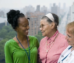 Menschen verschiedener Hautfarben und Alter stehen einander zugewandt vor urbanem Hintergrund